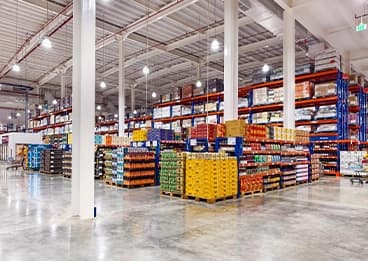 Spacious wholesale warehouse aisle stocked with colorful palletized goods on metal shelves Spacious wholesale warehouse aisle stocked with colorful palletized goods on metal shelves
