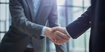 100% Foreign Ownership Two businessmen shaking hands with UAE city skyline in background